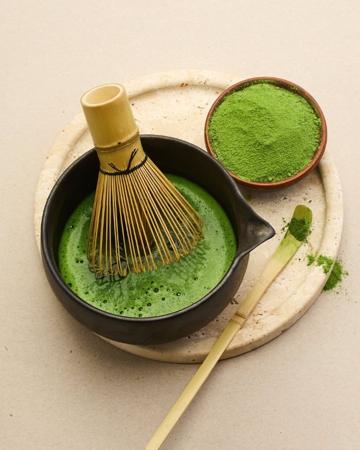 Bowl of vibrant emerald green matcha with a bamboo whisk